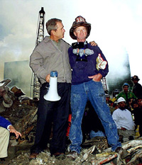 As rescue efforts continued in the rubble of the World Trade Center, Bush put his arms around firefighter Bob Beckwith while standing in front of the World Trade Center debris, Friday, September 14, 2001. Bush is standing on a burned fire truck. (AP Photo/Doug Mills)